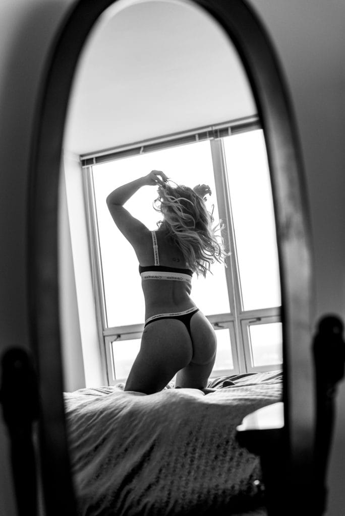 woman black and white back shot kneeling pose on top of the bed